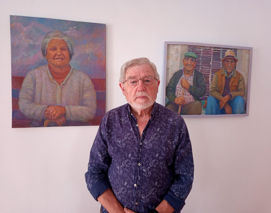 Juan Molino junto a dos de sus cuadros de la serie Convecinos